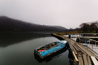 Boat moored in lake against sky