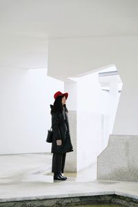 Full length of woman standing against wall