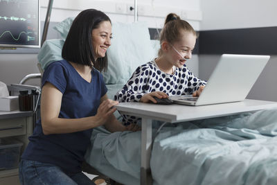 Mother and daughter looking at laptop in hospital