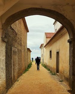 Rear view of people walking on narrow alley amidst buildings