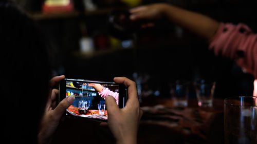 Female tourist using smartphone to record video of tea maker in counter cafe community at chiang rai 