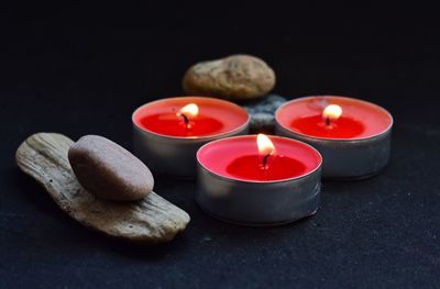 Close-up of lit tea light candles and stones on table