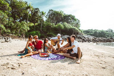 People sitting on beach against sky