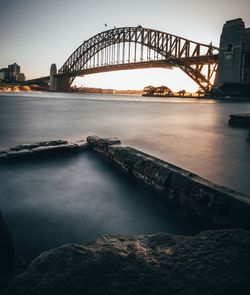 Bridge over river against clear sky during sunset