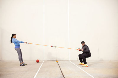 Coach training athlete for stretching muscles against wall