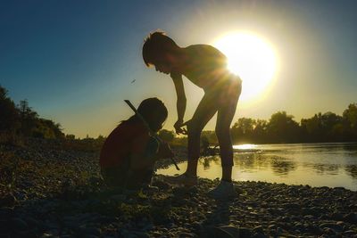 Silhouette people against bright sun during sunset