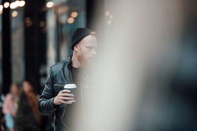 Young man drinking coffee in city