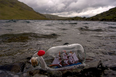A little bottled ship in a mountain lake in the british highlands