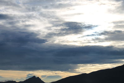 Low angle view of silhouette mountains against dramatic sky