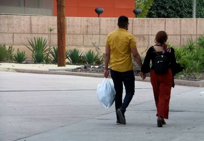 Rear view of people walking on footpath