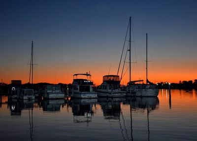 Sailboats in sea at sunset