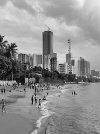 People on beach against cloudy sky