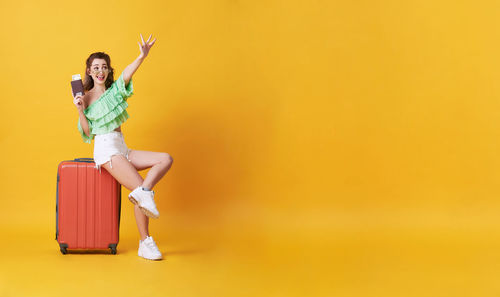 Full length of a young woman against yellow background