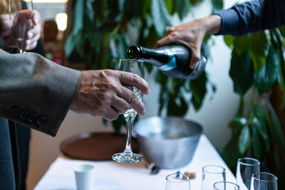 Midsection of man pouring wine in glass