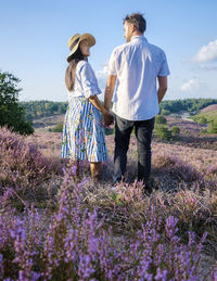 Rear view of couple walking on field