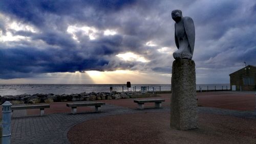 Statue in sea against cloudy sky