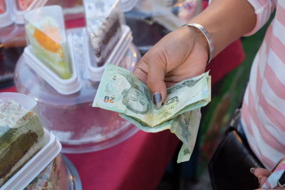 Midsection of woman holding paper currency at market