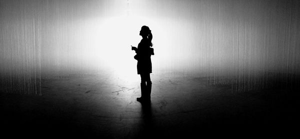 Silhouette woman standing against wall