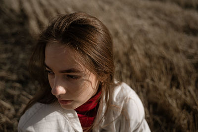 Close-up young woman looking away standing on field