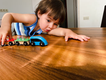 Boy playing with toy on hardwood floor at home