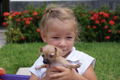 Close-up of cute girl holding puppy in garden