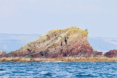 Rock formations by sea against clear sky