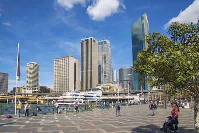 People on modern buildings in city against sky