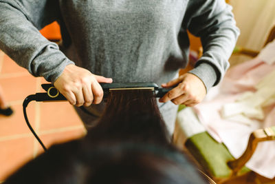 Midsection of beautician working on customer hair in salon