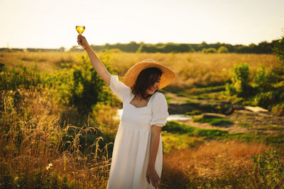 Young beautiful girl in a white dress having a picnic with a glass of champagne or white wine