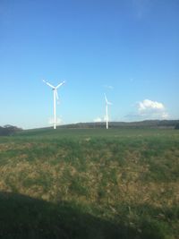 Windmills on field against sky