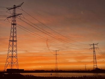 Low angle view of electricity pylon against sky during sunset