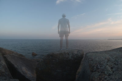 Rear view of man looking at sea against sky