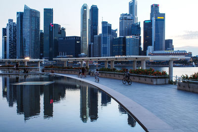 Modern buildings by river against sky in city