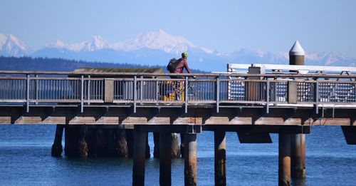 Man riding bicycle on pier over river