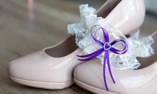 Close-up of purple tied ribbon on white lace garter over high heels