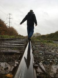 Rear view of man standing on railroad track