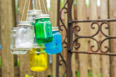 Close-up of multi colored glass bottle against fence