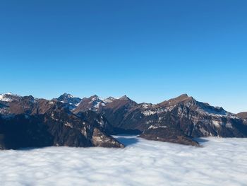 Scenic view of snowcapped mountains against clear blue sky