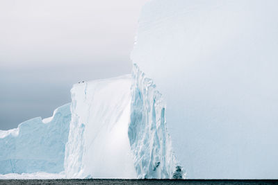 Iceberg against cloudy sky