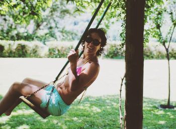 Portrait of woman enjoying on swing in park