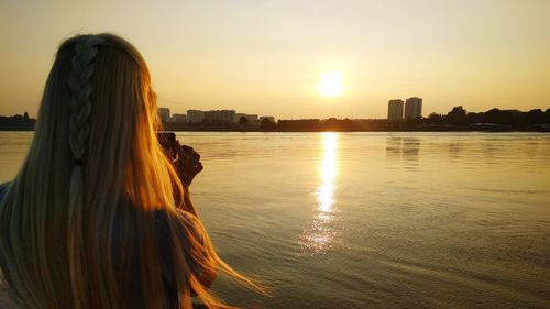 Rear view of woman photographing at sunset