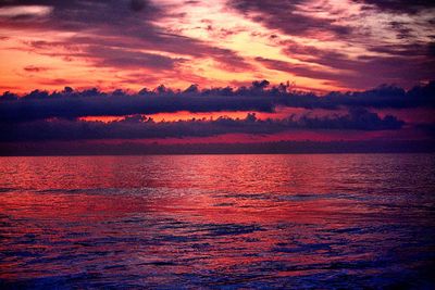 Scenic view of sea against dramatic sky during sunset