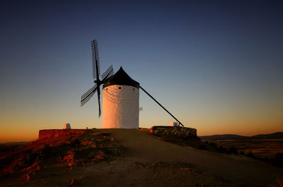 Traditional windmill against clear sky during sunset