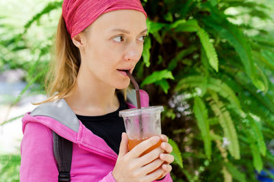 Woman looking away while drinking outdoors