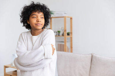 Portrait of young woman sitting on bed at home