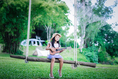 Full length of woman sitting on grass against trees