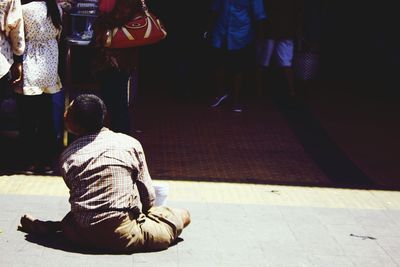 Beggar sitting on road in city