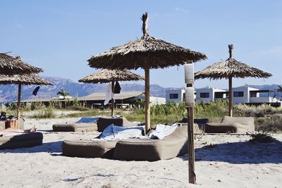 Lounge chairs by swimming pool at beach against sky