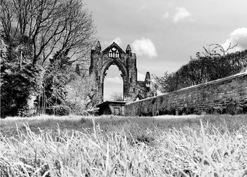 Arch bridge on field against sky