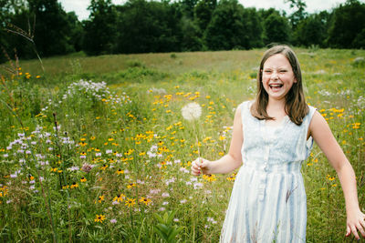 Girl laughing as she picks wild flowers in a field